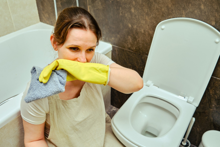 Woman covering nose while cleaning bathroom | Awesome Home Services
