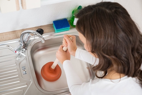 woman plunging the drain of her sink